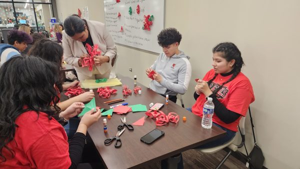 Elizabeth Arroyo teaches students from other schools how to make poinsettias for the posada.