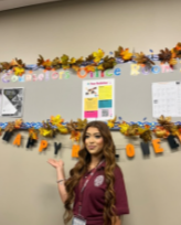 Senior Diana Carreno checks herself against a fall decorated bulletin board to see if maroon and khaki match with this year's fall color scheme.