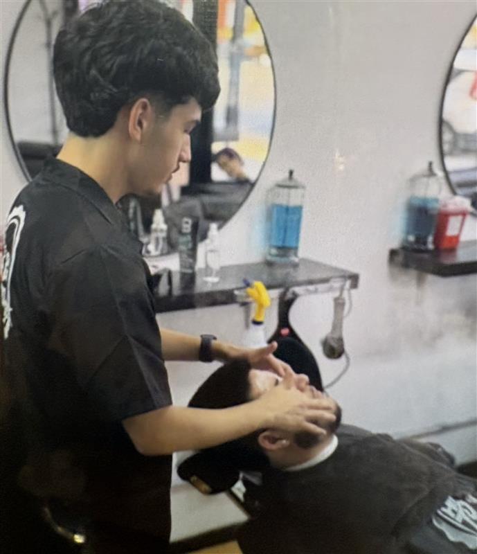 Ivan Haro gives his client a facial at How to Fade Hair Barber School.