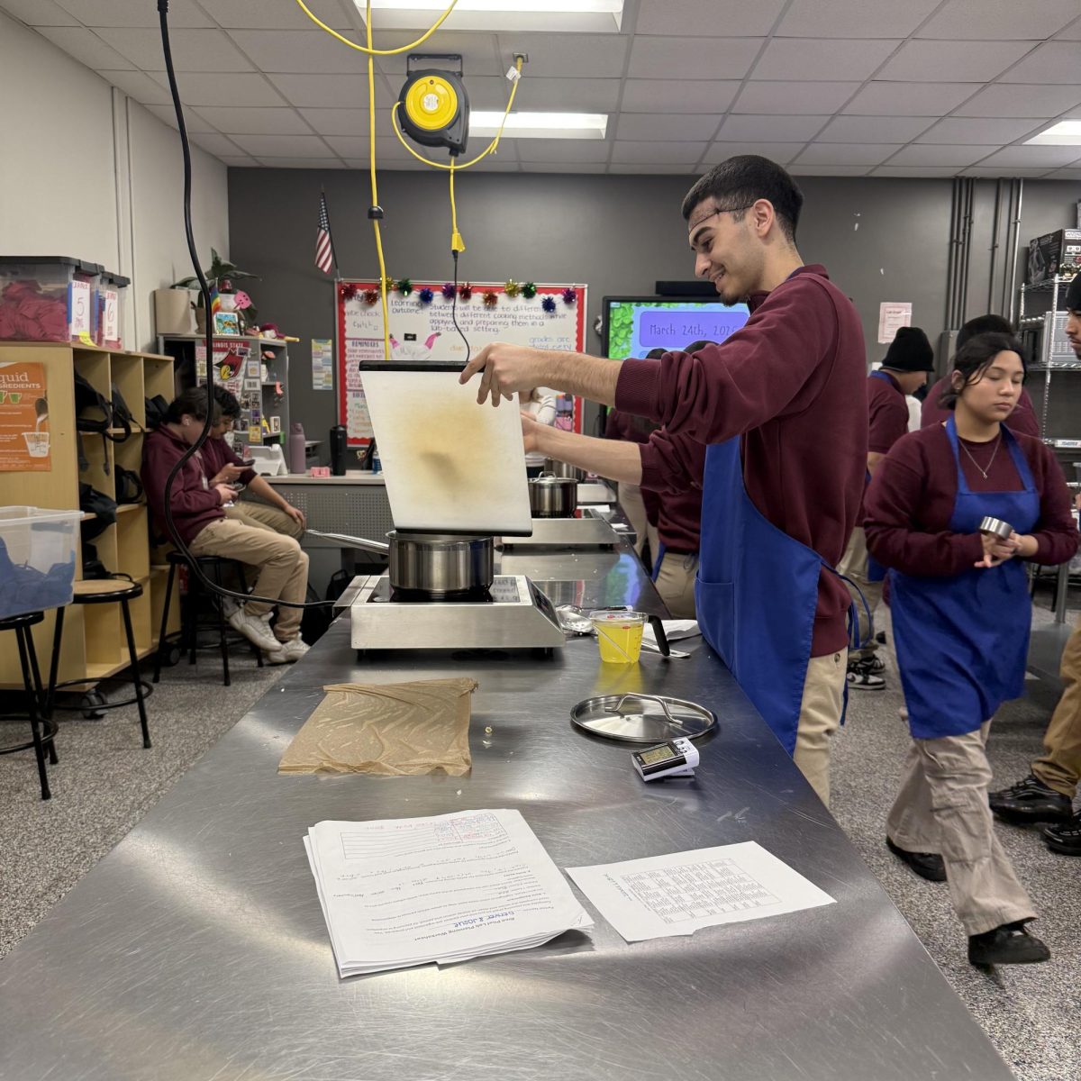 Sophomore Josue Vazquez carefully pours ingredients into a pot during a cooking lab as classmates work around him in class. “It’s actually kind of fun -- like you get to do something instead of just sitting there all class; maybe I'll cook over spring break,” Vazquez said.