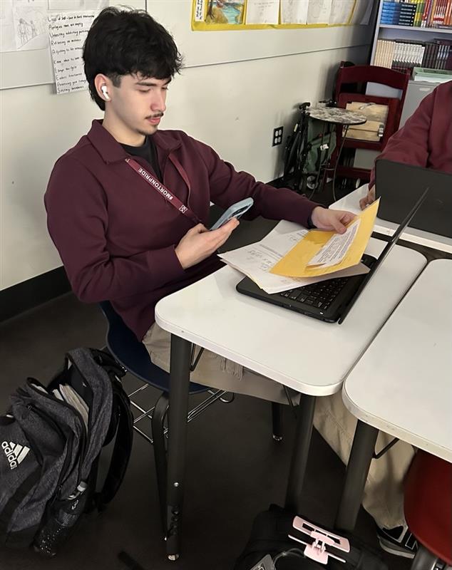 Senior Ivan Haro stops work to check his phone. 