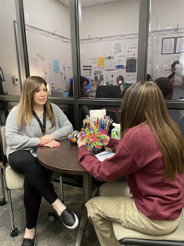 A student speaks with social worker Ms. Rivera after meeting with a counselor and deciding she needs additional support.